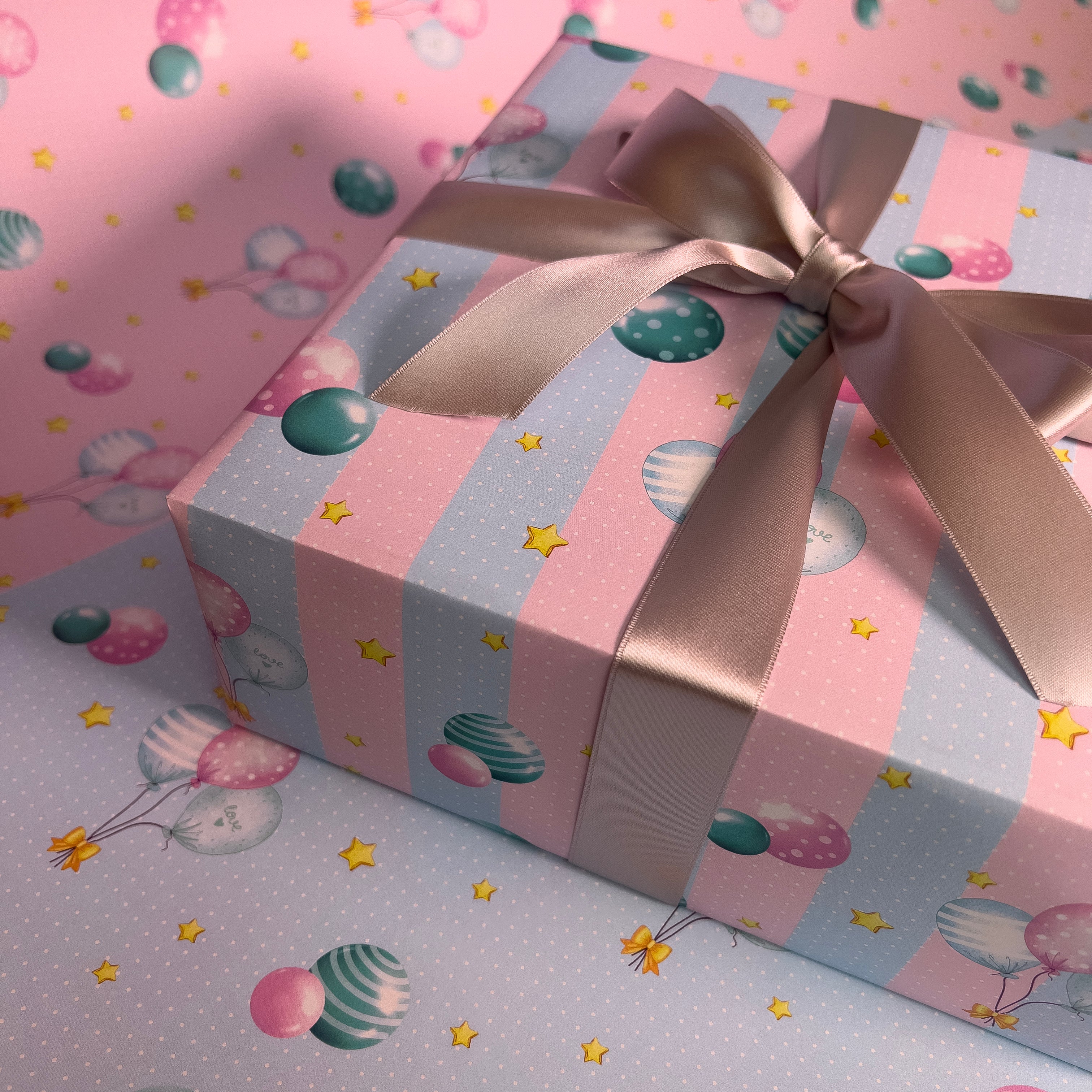 Gift wrapped in striped balloon wrapping paper with a satin ribbon bow.