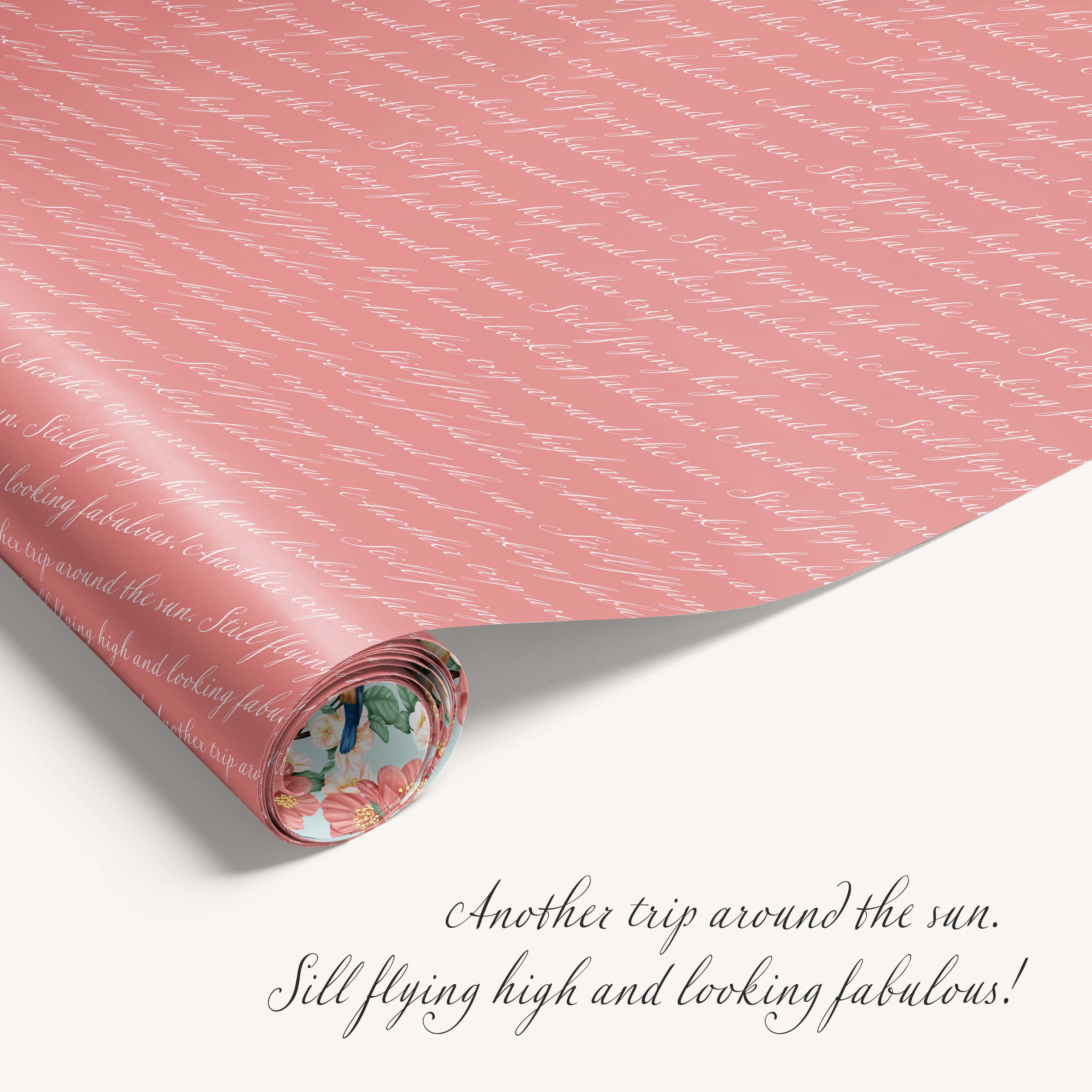 Roll of pink wrapping paper with text and a floral border on a white background