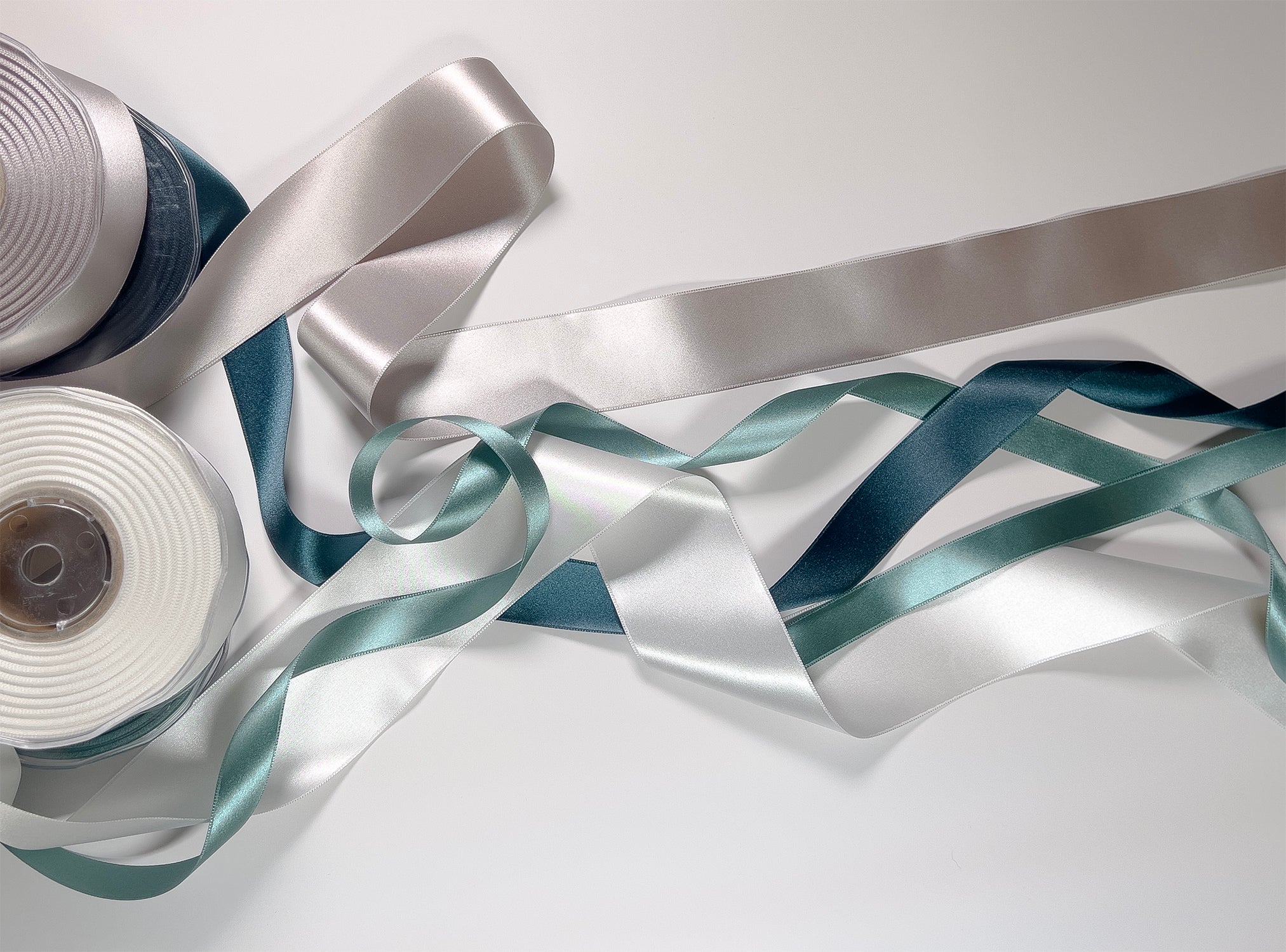 Silver and blue ribbons with spools on a white background