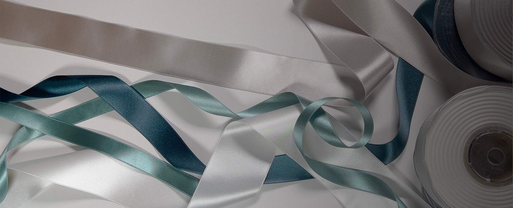 Roll of silver ribbon with a spool on a white background