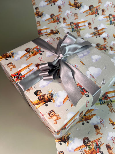 Gift wrapped in paper with airplane and character design, tied with a silver ribbon.