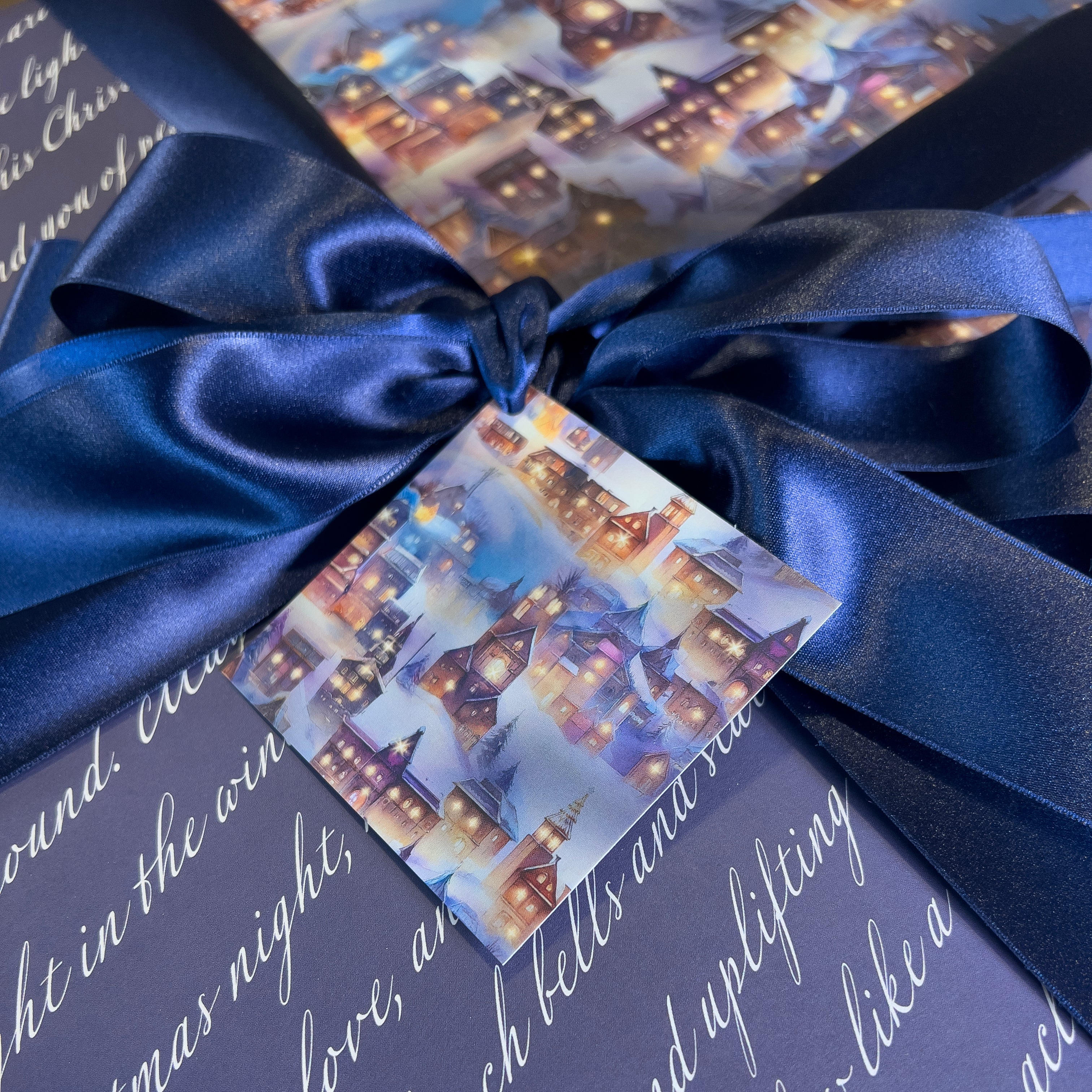 Gift box with blue ribbon and festive card featuring a snowy village scene.