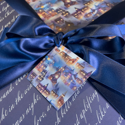Gift box with blue ribbon and festive card featuring a snowy village scene.